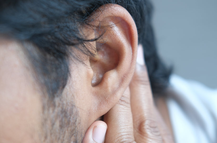 Closeup of someone's hand holding hair out of the way to show the ear.